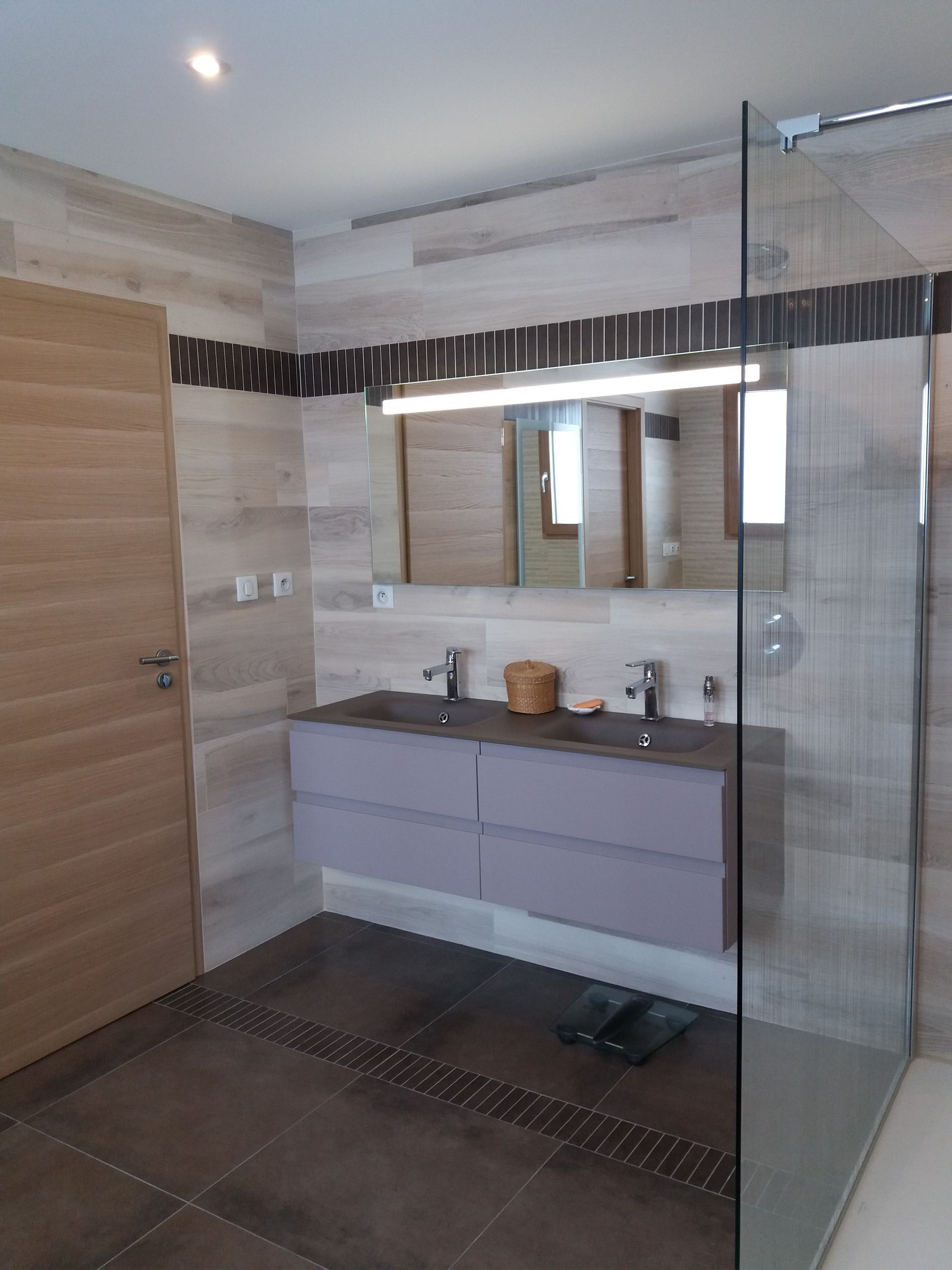 Meuble double vasque avec un miroir à côté d'une douche.