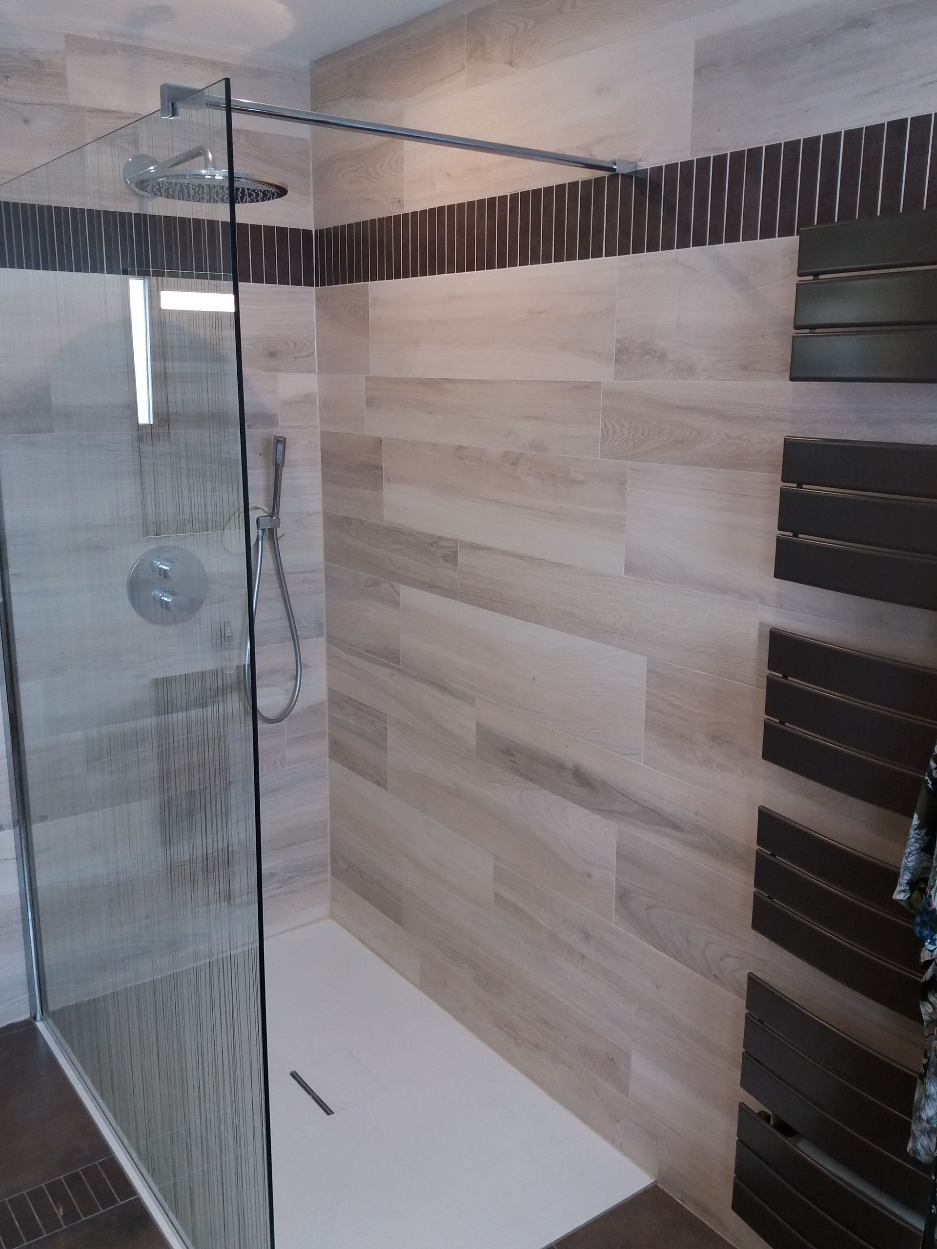 Douche à l'italienne avec le bac de douche, une paroi en verre et le carrelage.