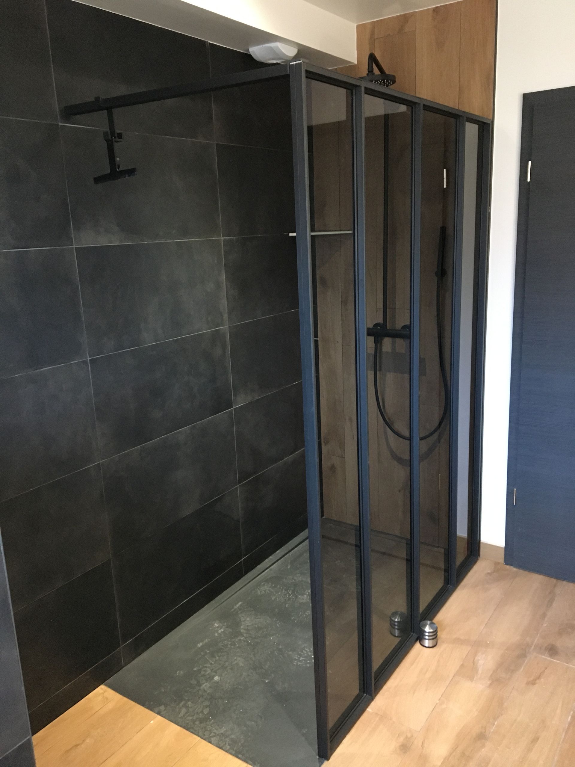 Douche à l'italienne avec le carrelage gris et paroi de douche en verre.