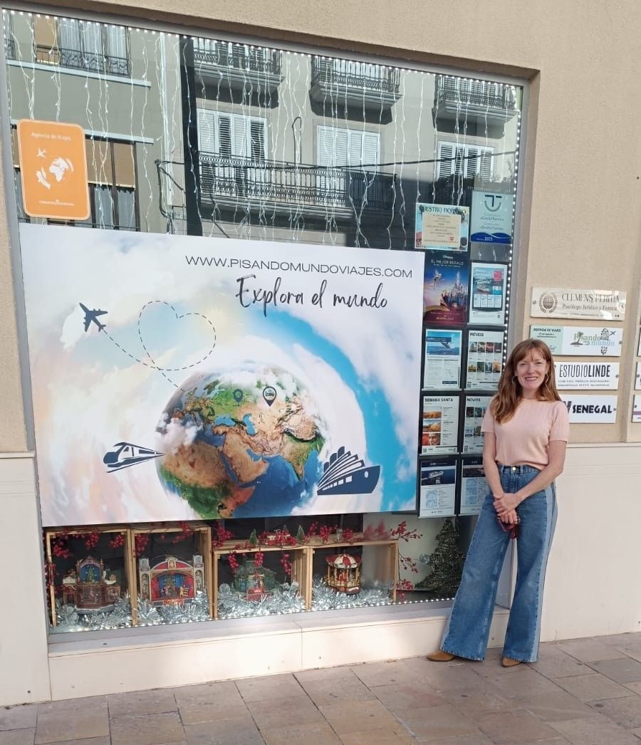 Mujer de pie junto a un colorido cartel publicitario en un escaparate sobre "Explorador de plantas".