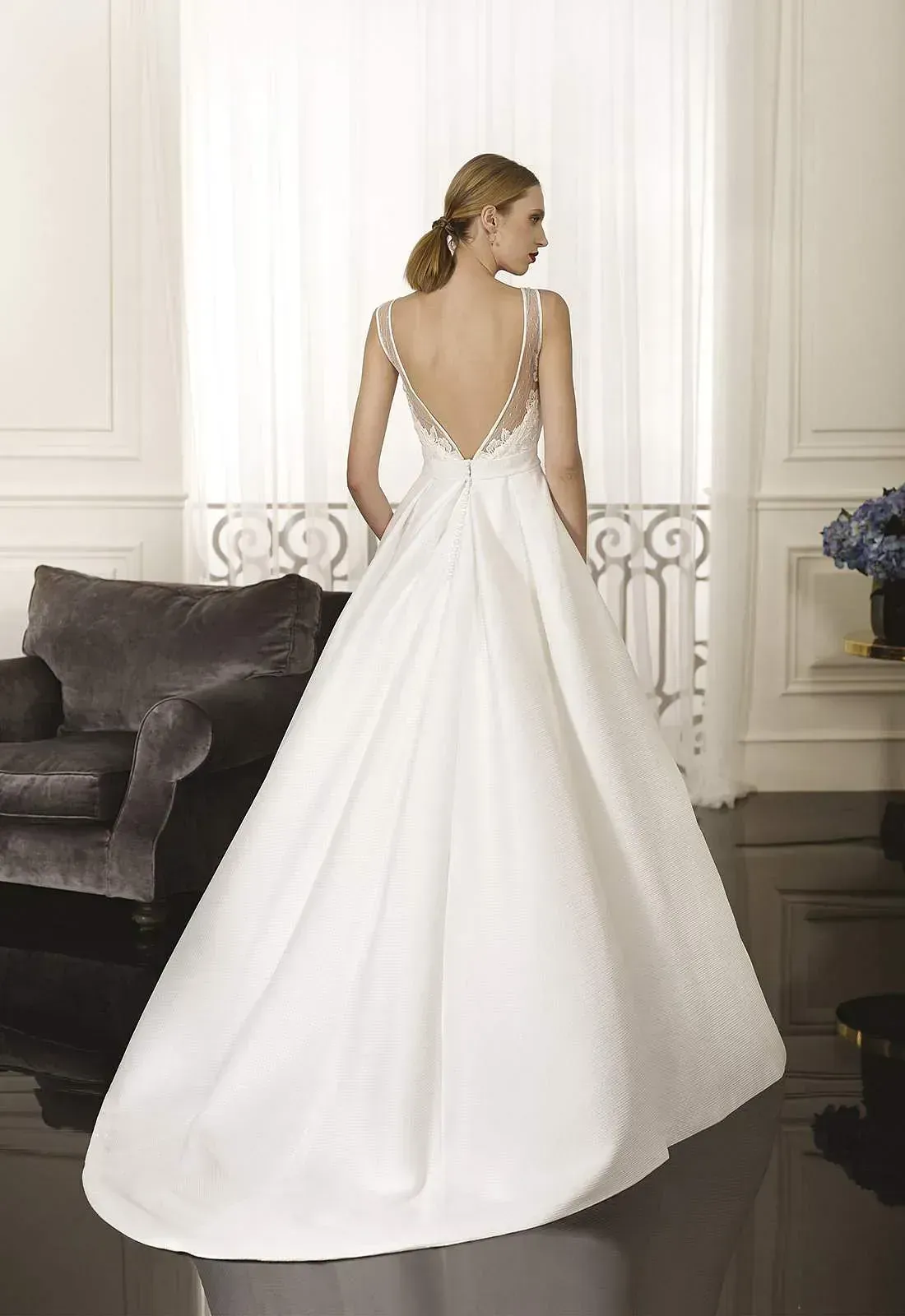 Una mujer con un vestido de novia blanco está de pie en una sala de estar.