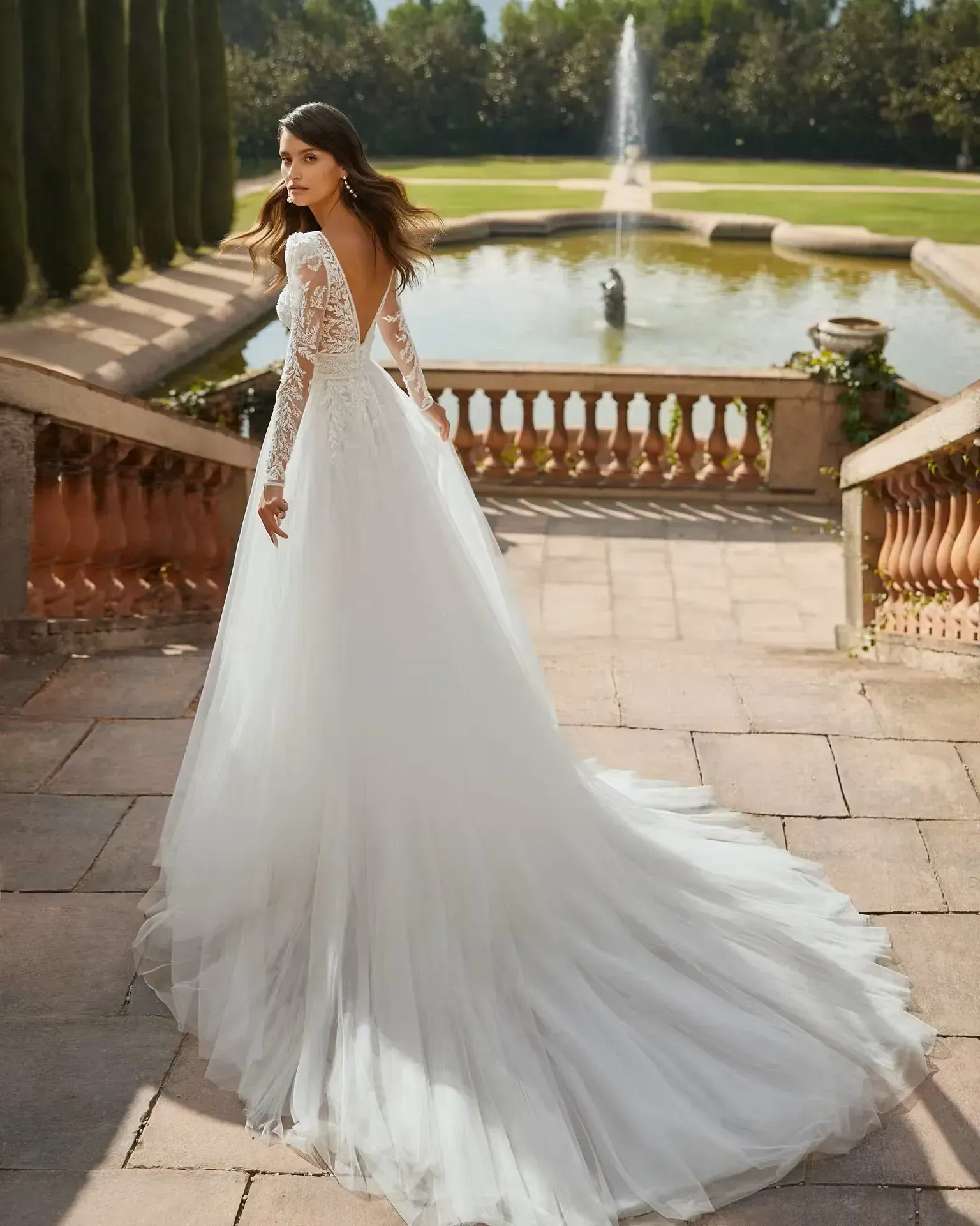 Una mujer con un vestido de novia está parada frente a una fuente.