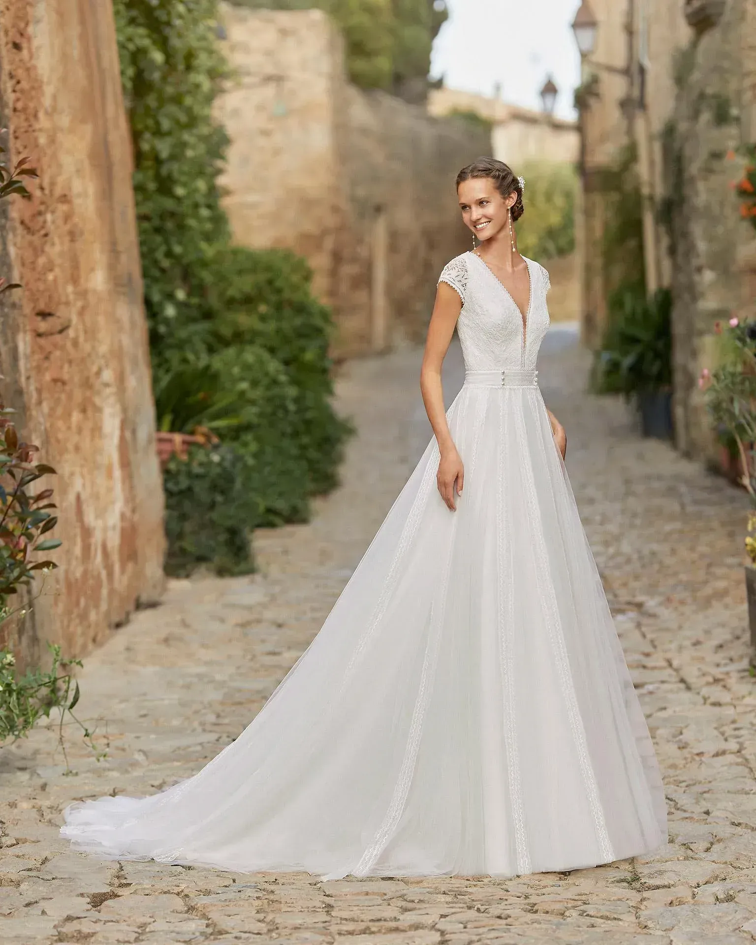 Una mujer con un vestido de novia blanco está parada en una calle adoquinada.