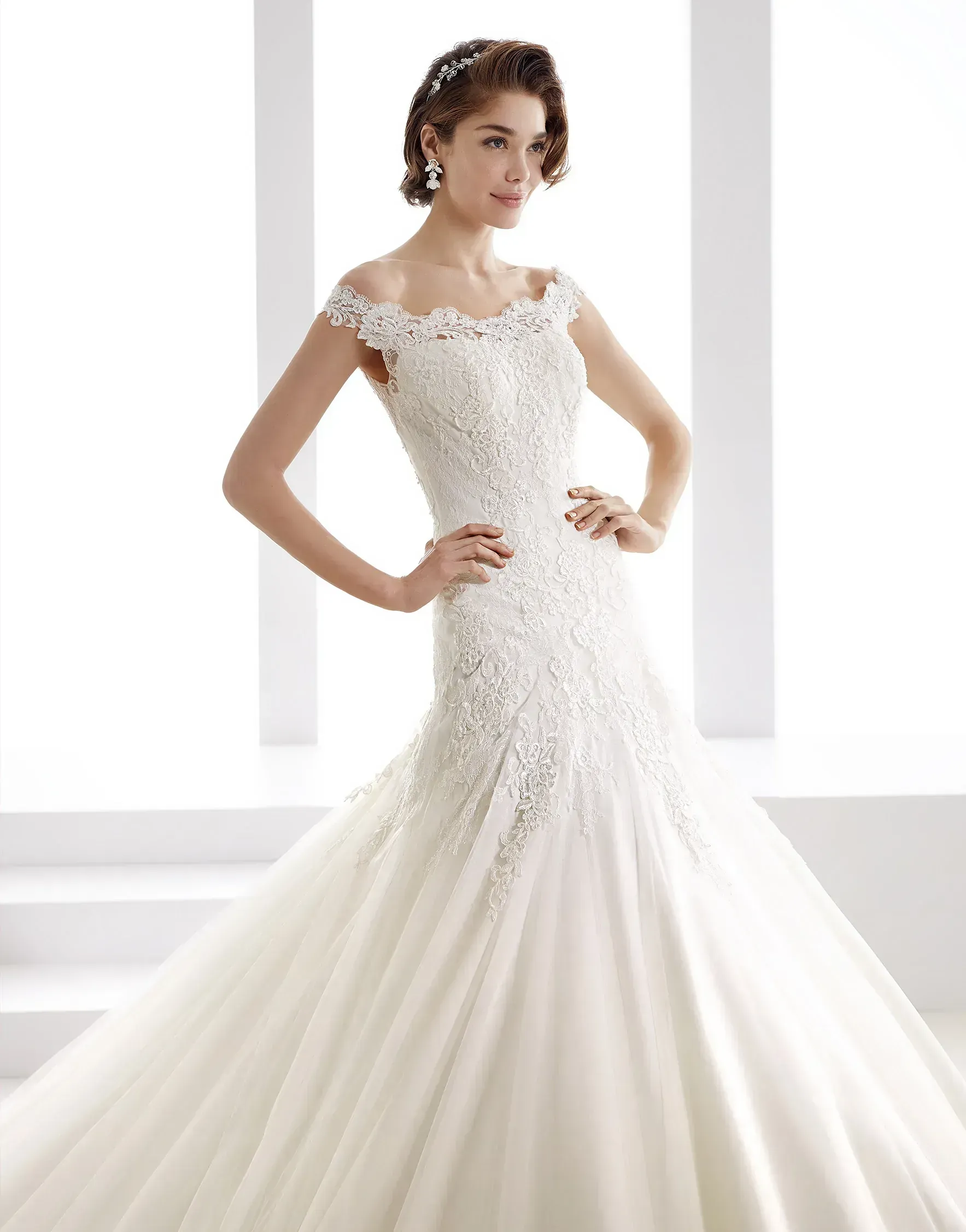 Una mujer con un vestido de novia blanco está parada frente a una ventana.