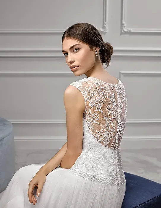 Una mujer con un vestido de novia blanco está sentada en un sofá.