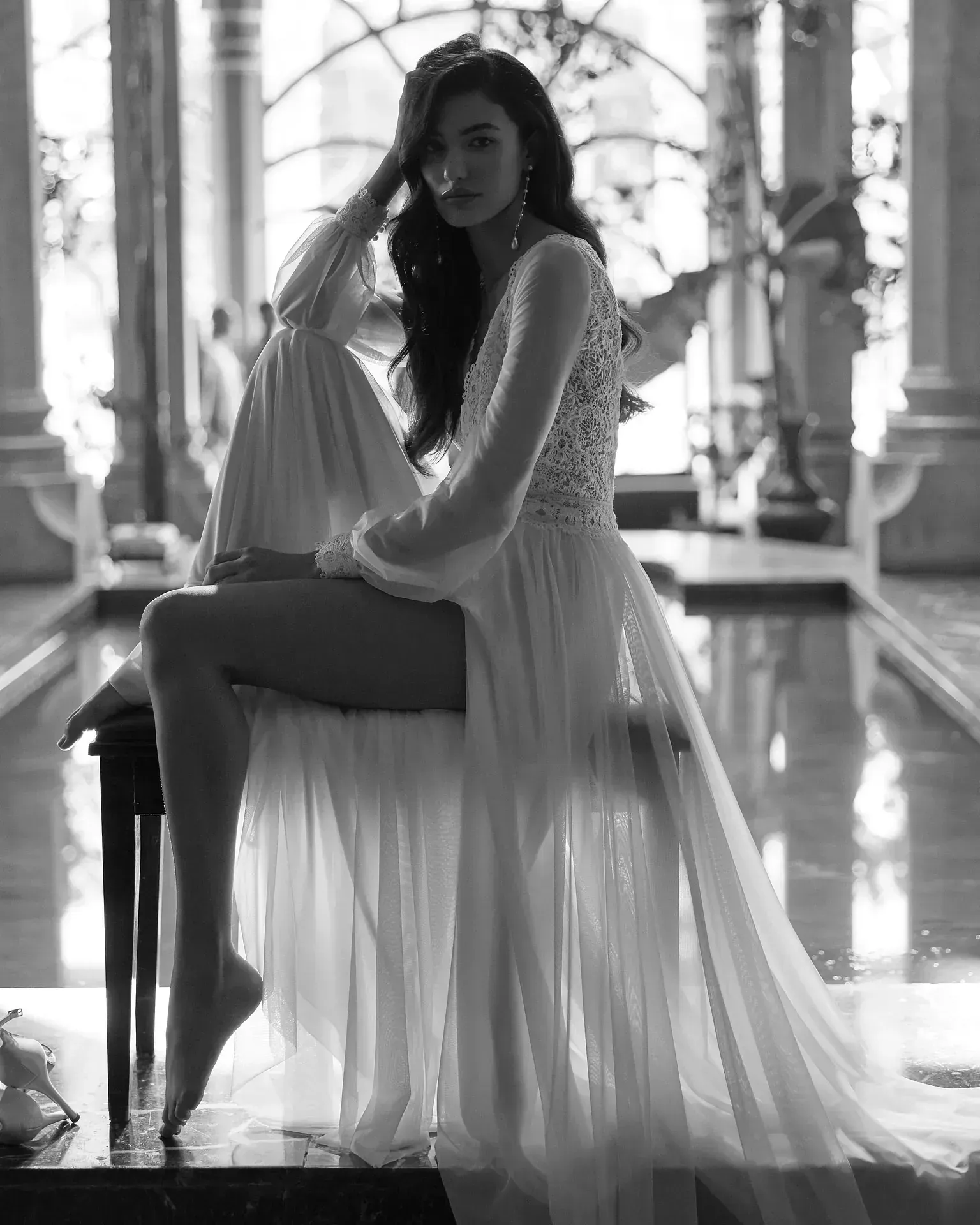 Una mujer con un vestido blanco largo está sentada en una silla.