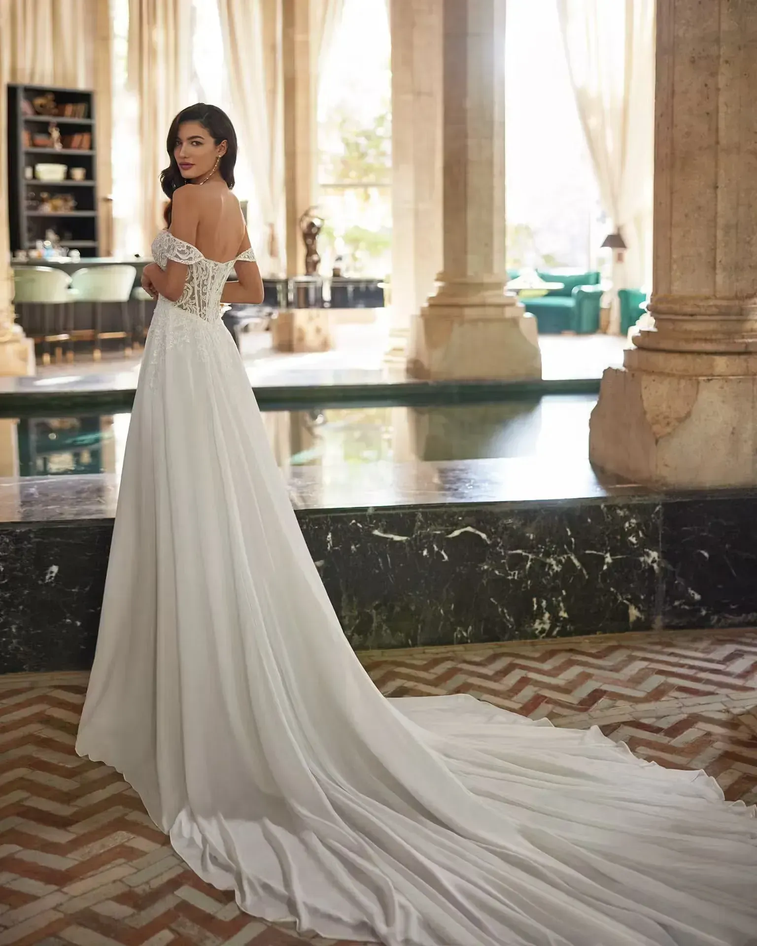 Una mujer con un vestido de novia blanco está de pie en una habitación con columnas.