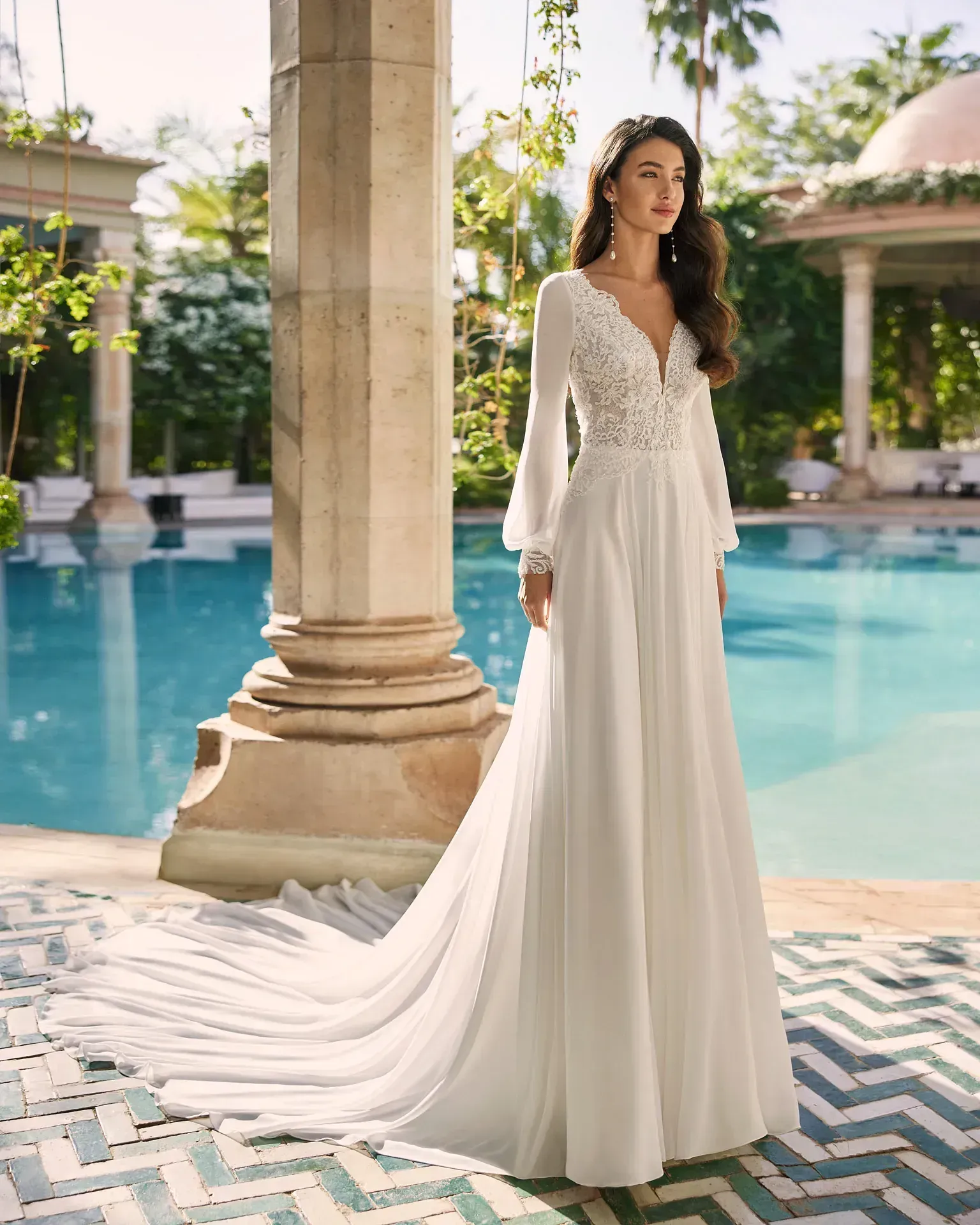 Una mujer con un vestido de novia blanco está de pie junto a una piscina.