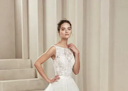 Una mujer con un vestido de novia blanco está parada frente a una pared.
