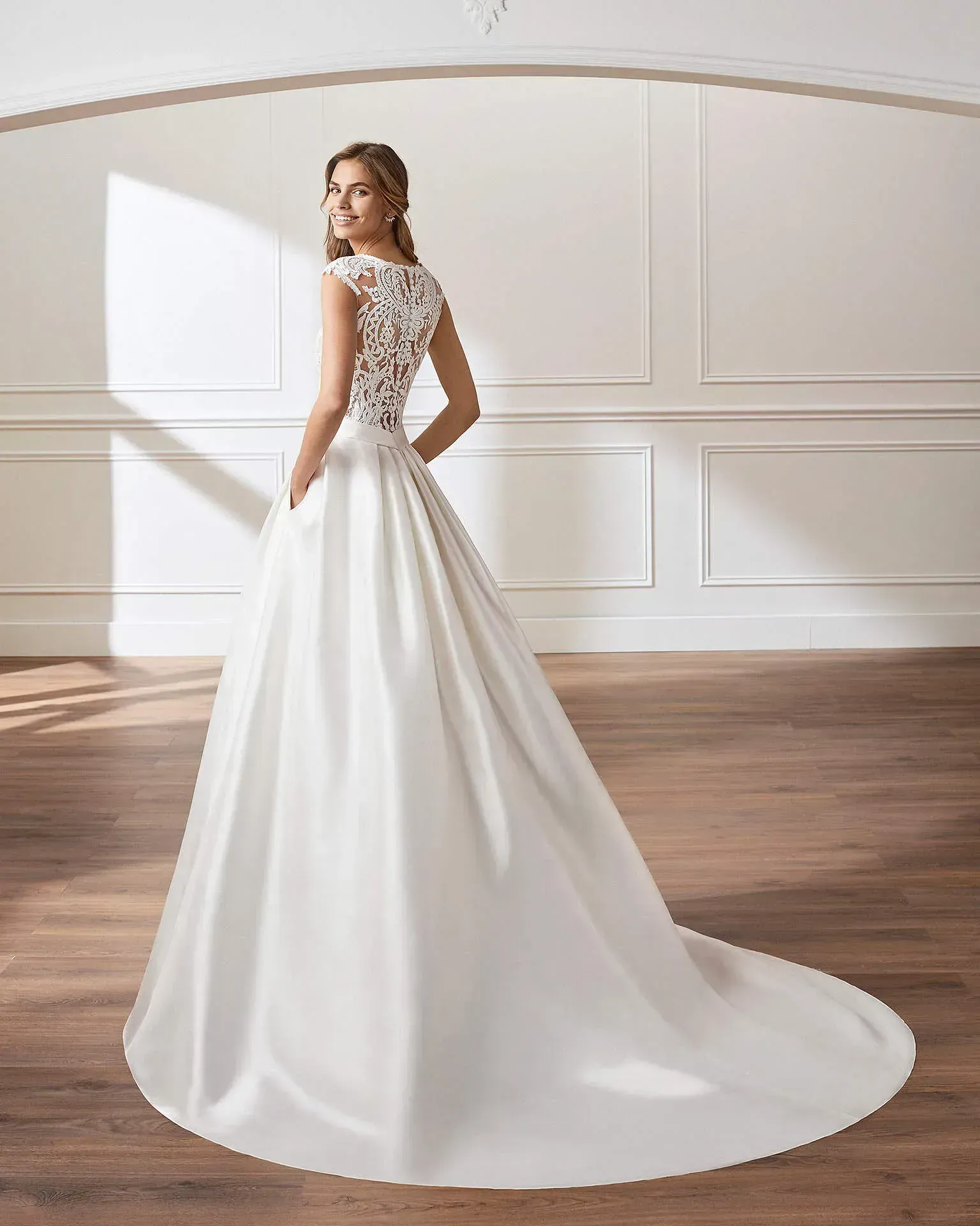 Una mujer con un vestido de novia blanco está de pie en una habitación.