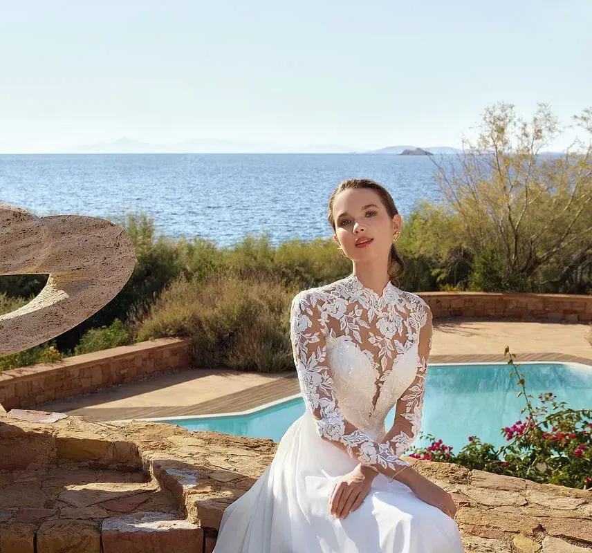 Una mujer con un vestido de novia está sentada junto a una piscina.