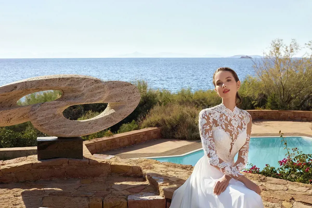 Una mujer con un vestido de novia está sentada junto a una piscina.