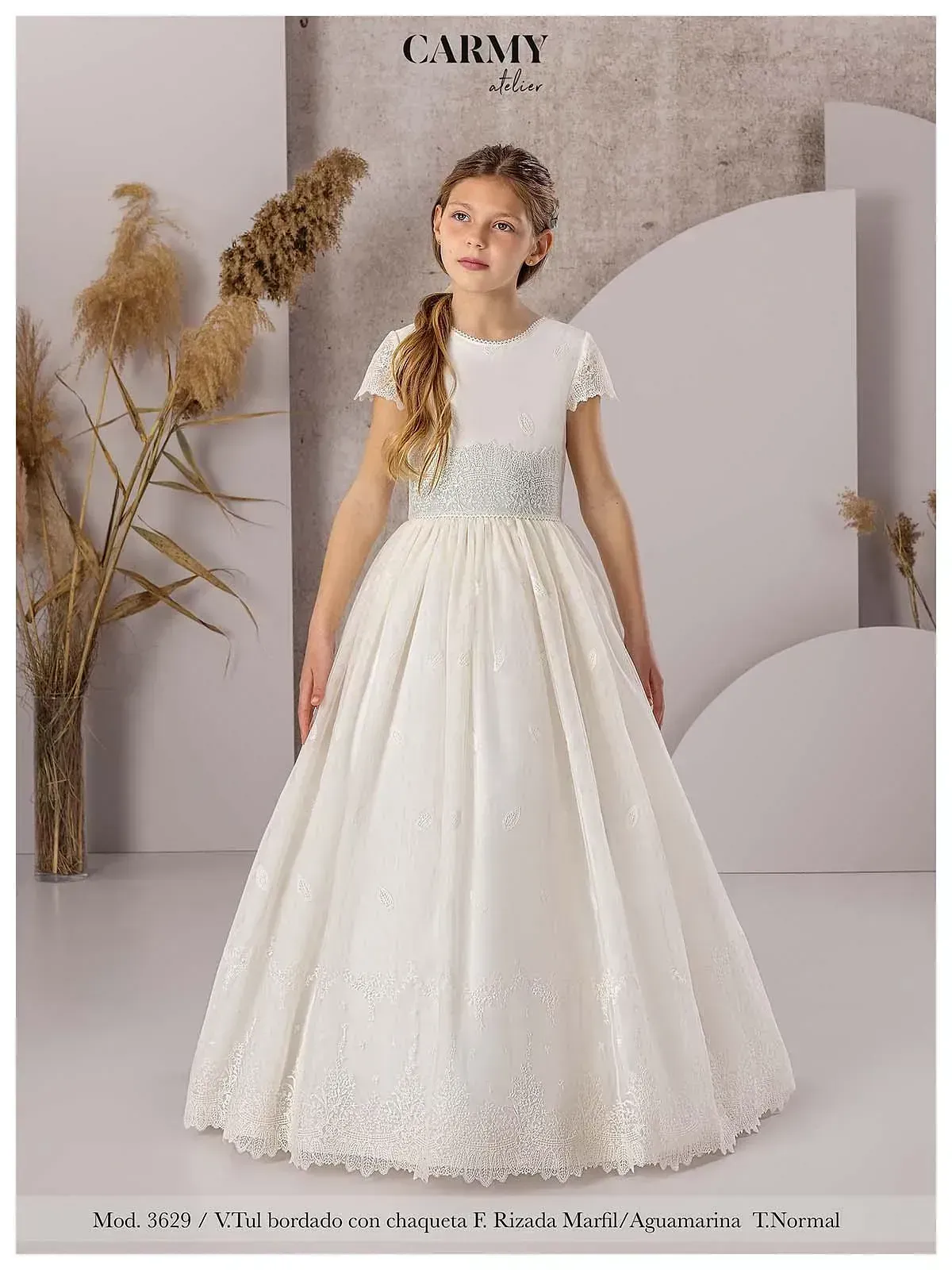 Una niña lleva un vestido de comunión blanco.
