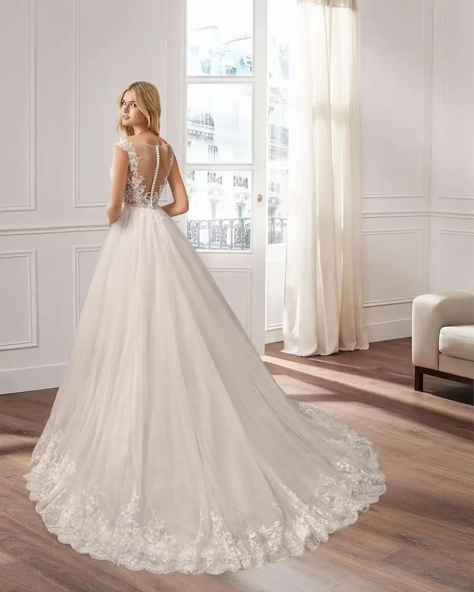 Una mujer con un vestido de novia blanco está de pie en una sala de estar.
