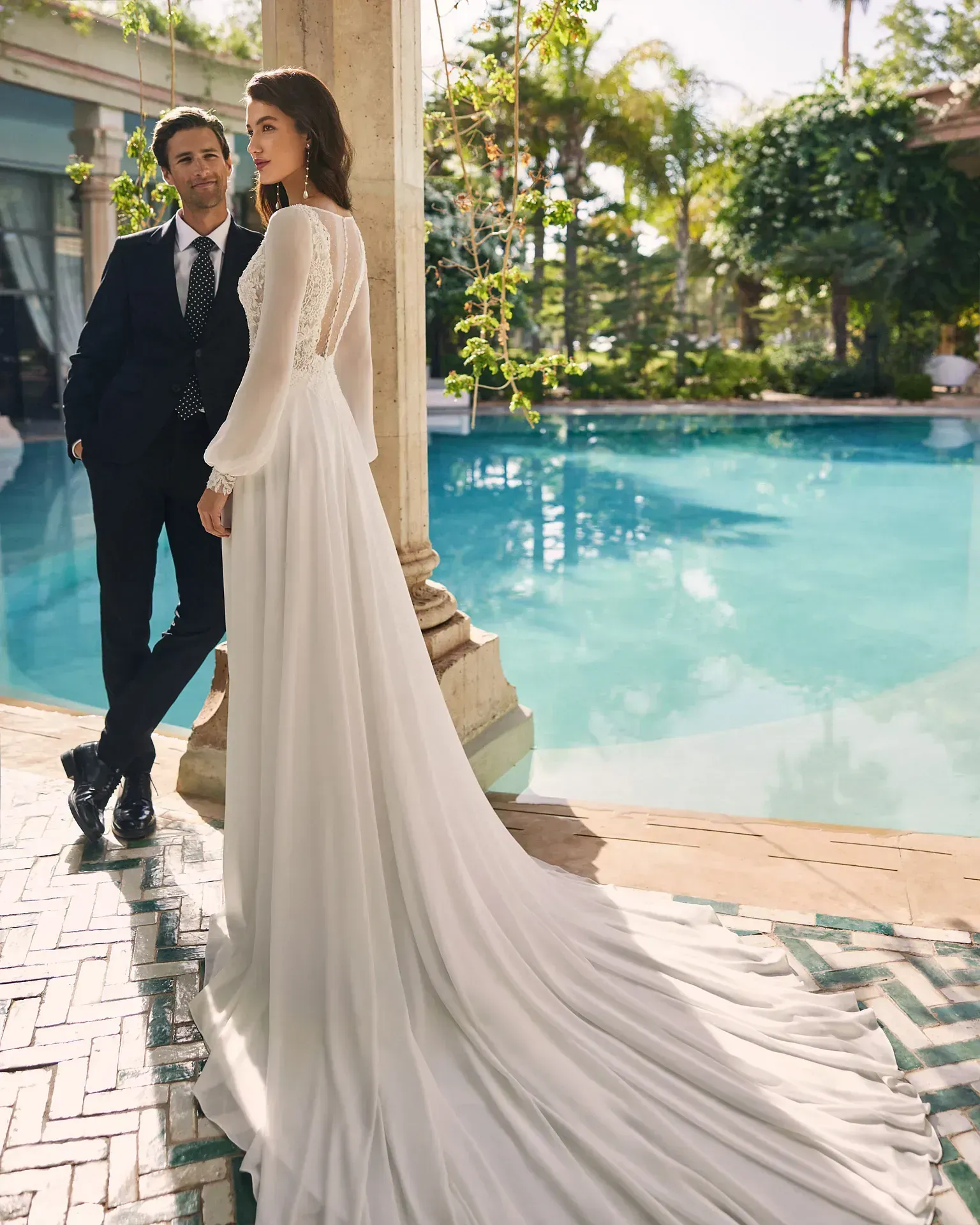 Una novia y un novio están de pie junto a una piscina.