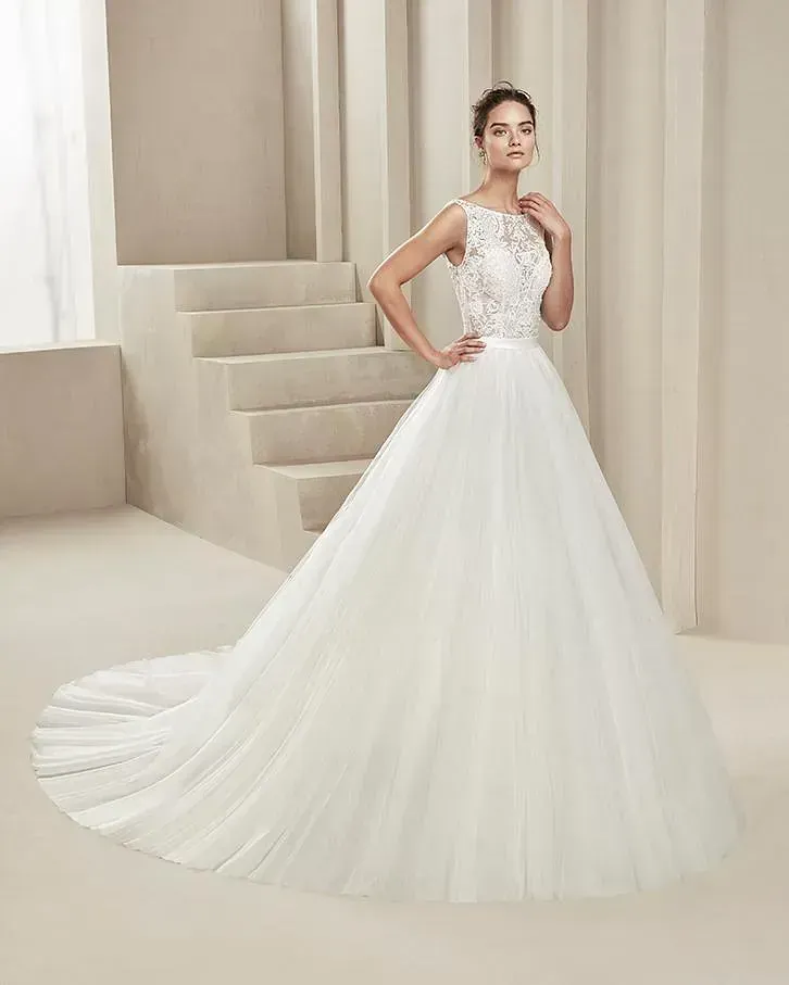 Una mujer con un vestido de novia blanco está parada frente a unas escaleras.