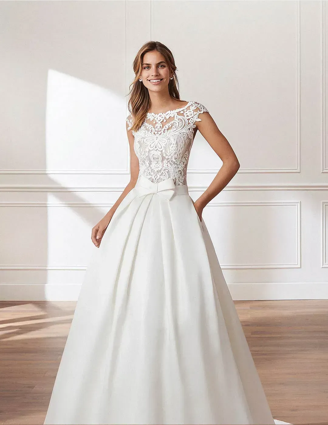 Una mujer con un vestido de novia blanco está de pie en una habitación.