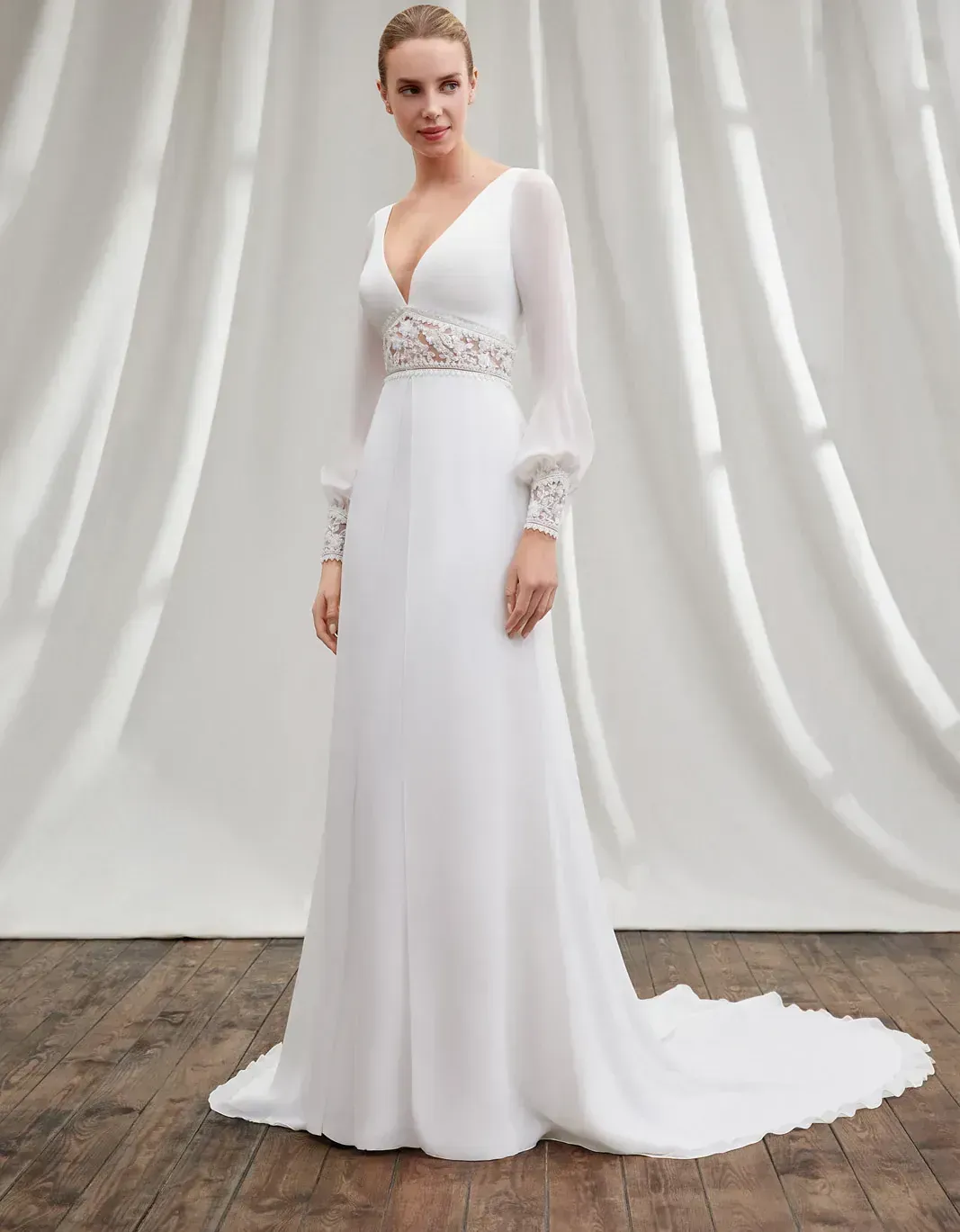 Una mujer lleva un vestido de novia blanco con mangas largas.