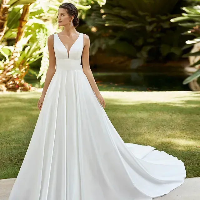 Una mujer lleva un vestido de novia blanco con una larga cola.