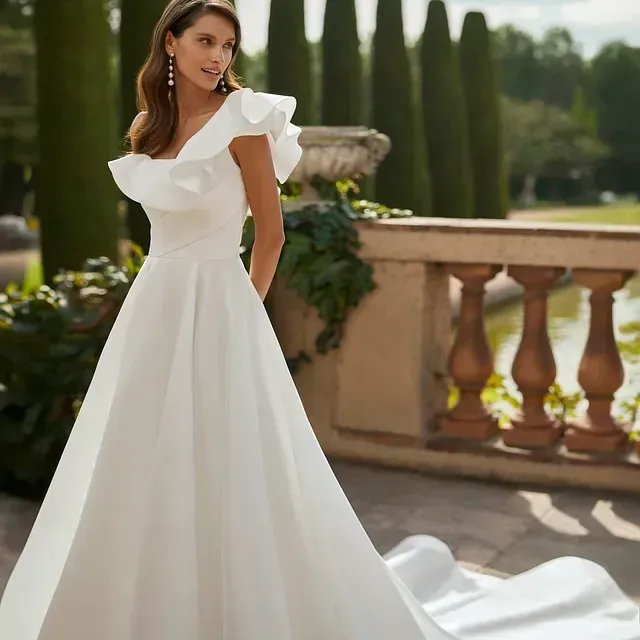 Una mujer con un vestido de novia blanco está de pie junto a una barandilla.