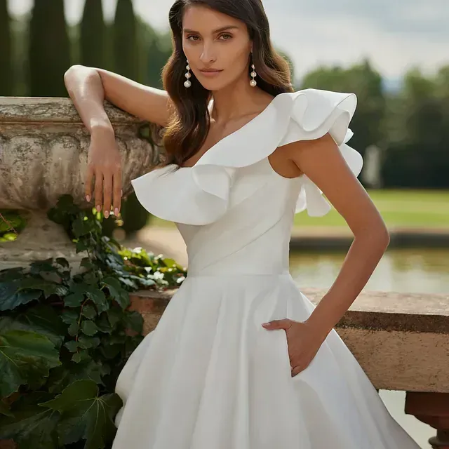 Una mujer con un vestido de novia blanco está apoyada contra una pared.