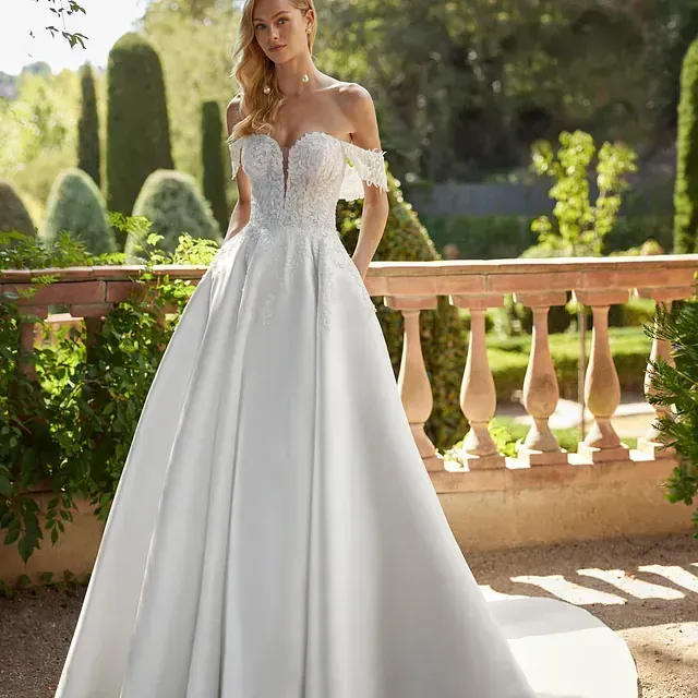 Una mujer con un vestido de novia blanco está de pie junto a una barandilla.