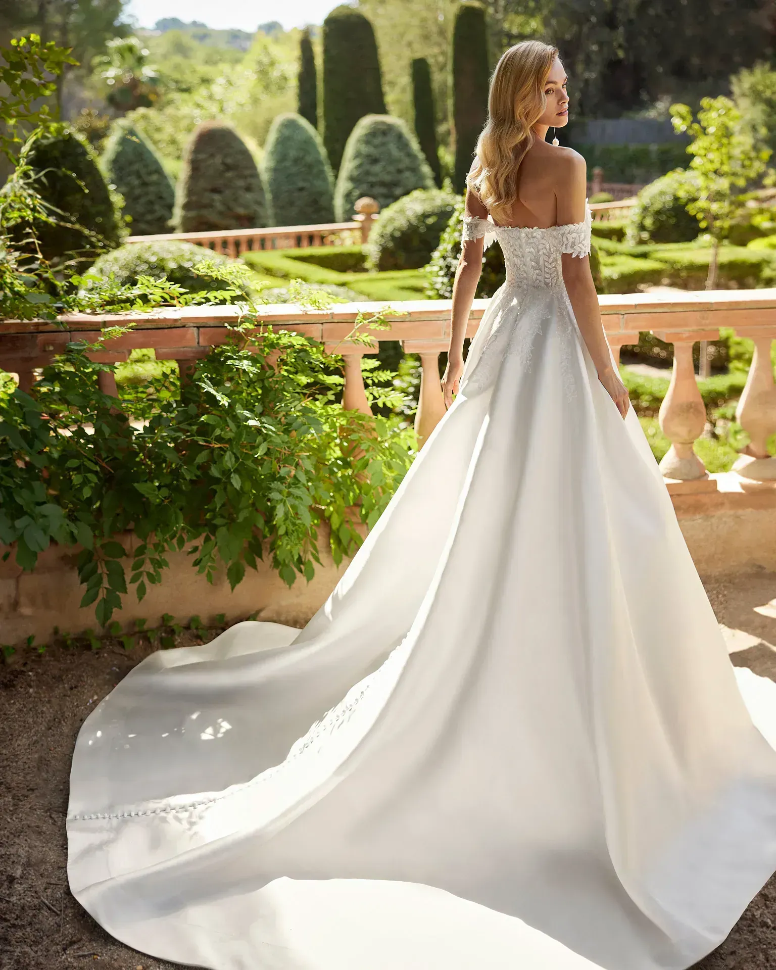 Una mujer con un vestido de novia blanco está de pie en un jardín.