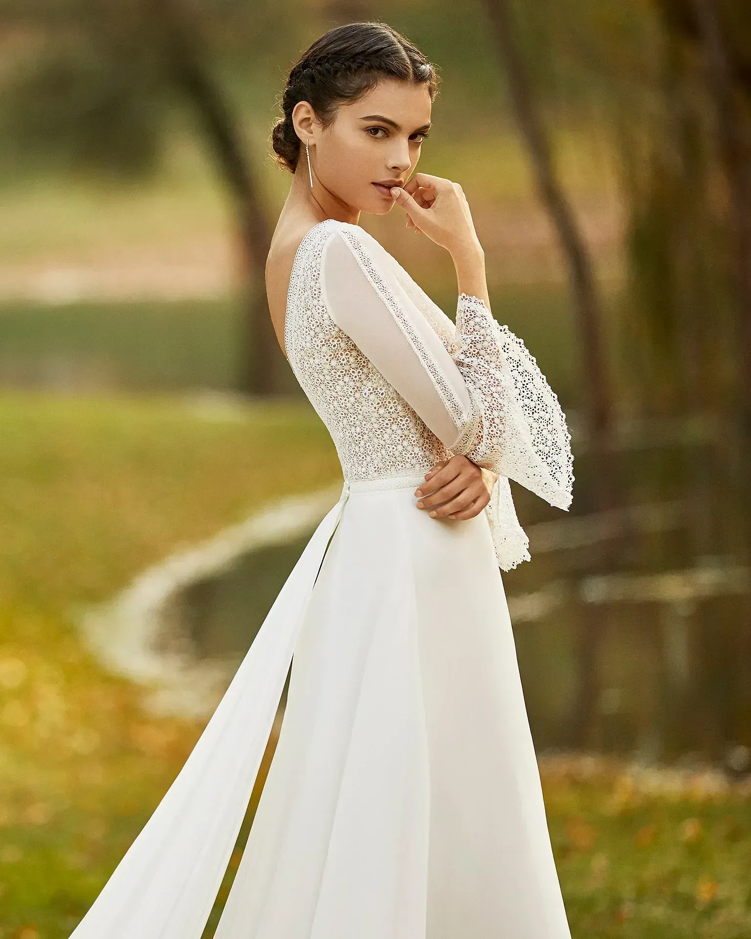 Una mujer con un vestido de novia blanco está parada en un campo.