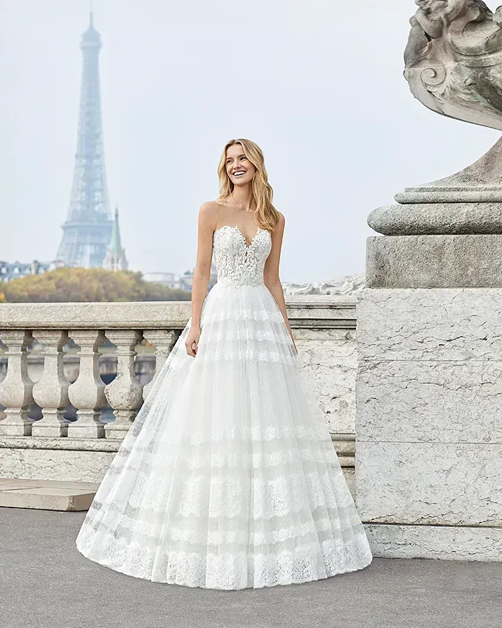 Una mujer con un vestido de novia blanco está parada frente a la Torre Eiffel.