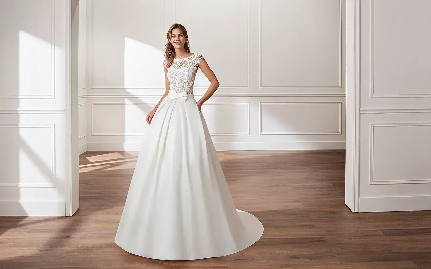 Una mujer con un vestido de novia blanco está de pie en una habitación.