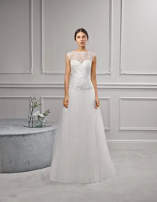 Una mujer con un vestido de novia blanco está de pie en una habitación.