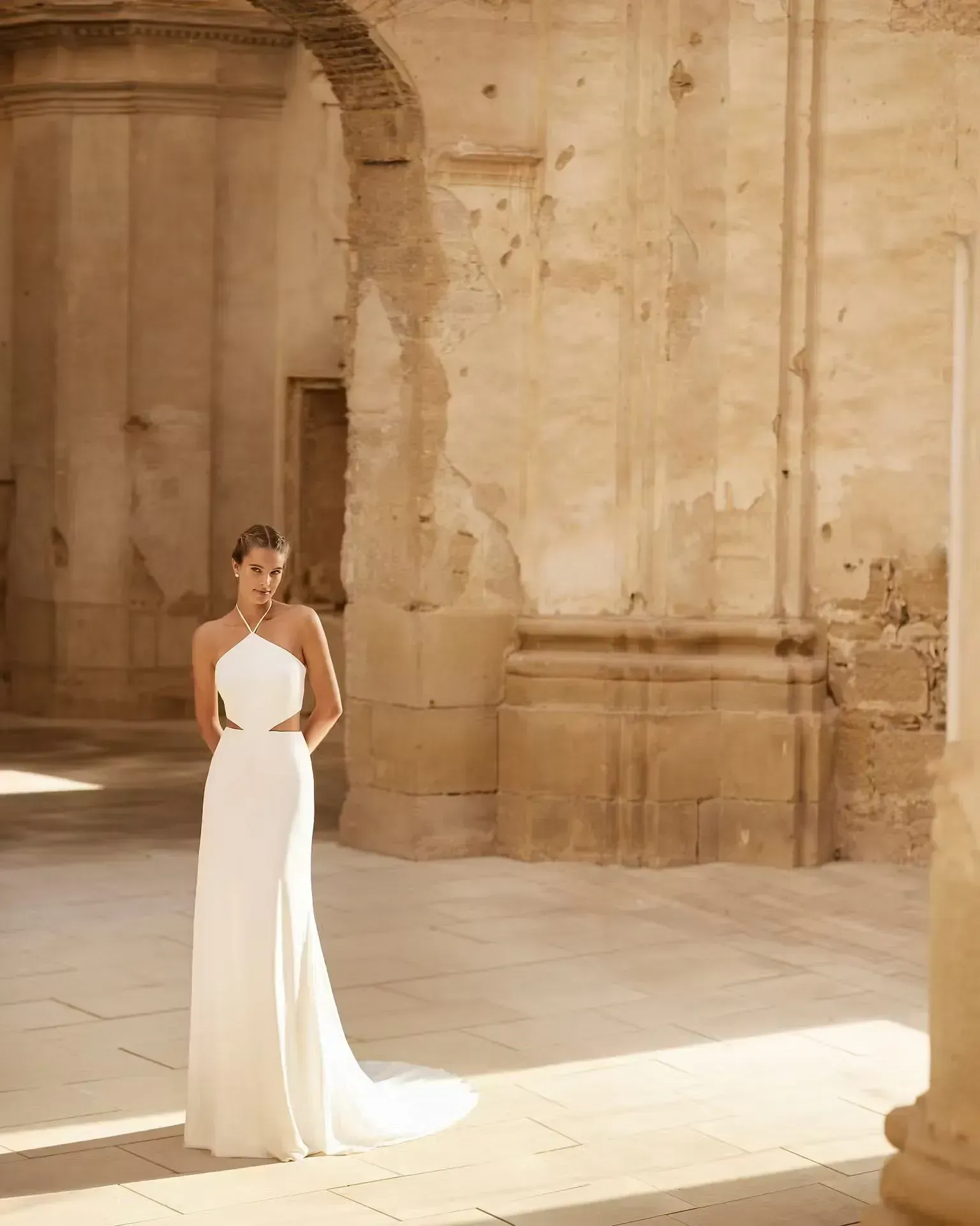 Una mujer con un vestido blanco está parada frente a un edificio.