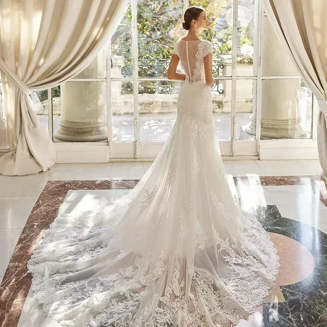 Una mujer con un vestido de novia está parada frente a una ventana.