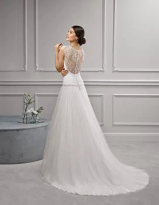 Una mujer con un vestido de novia blanco está de pie en una habitación.