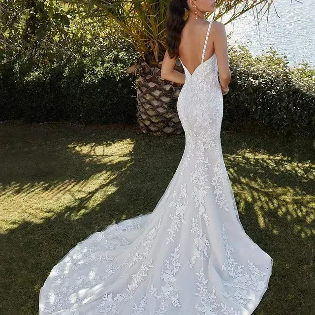 Una mujer con un vestido de novia blanco está parada frente a una palmera.