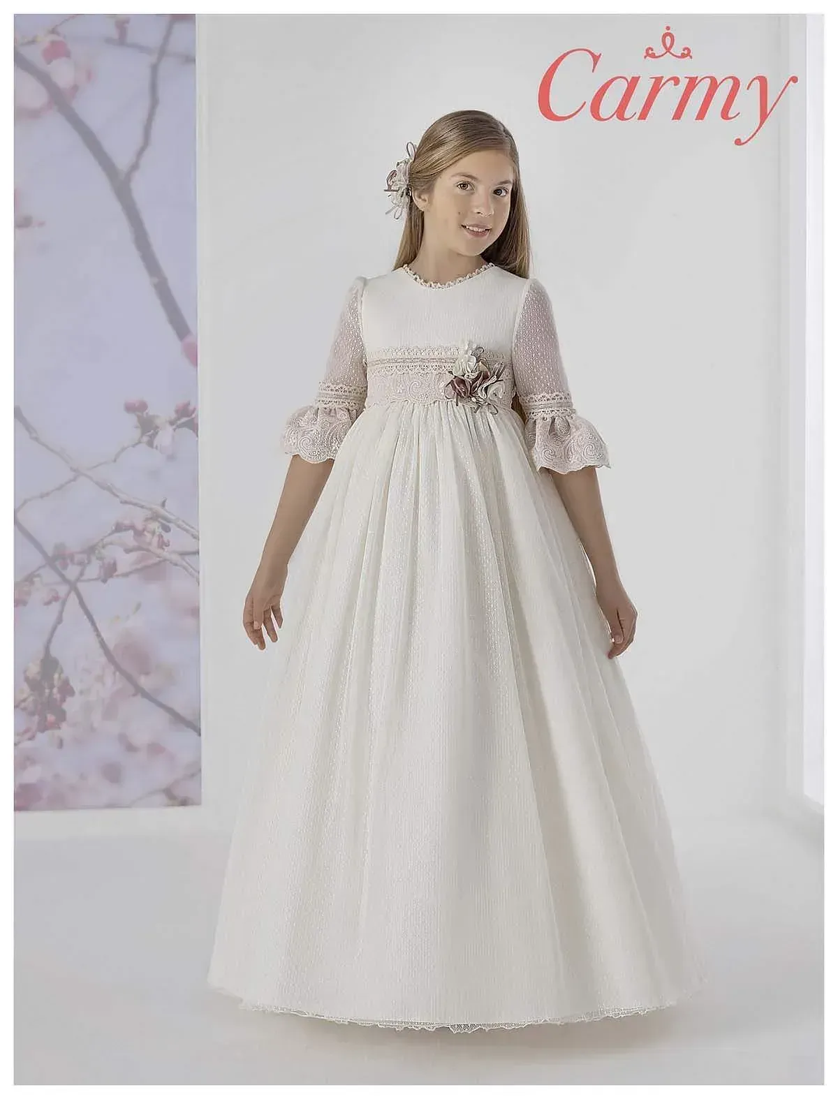 Una niña lleva un vestido de comunión blanco.