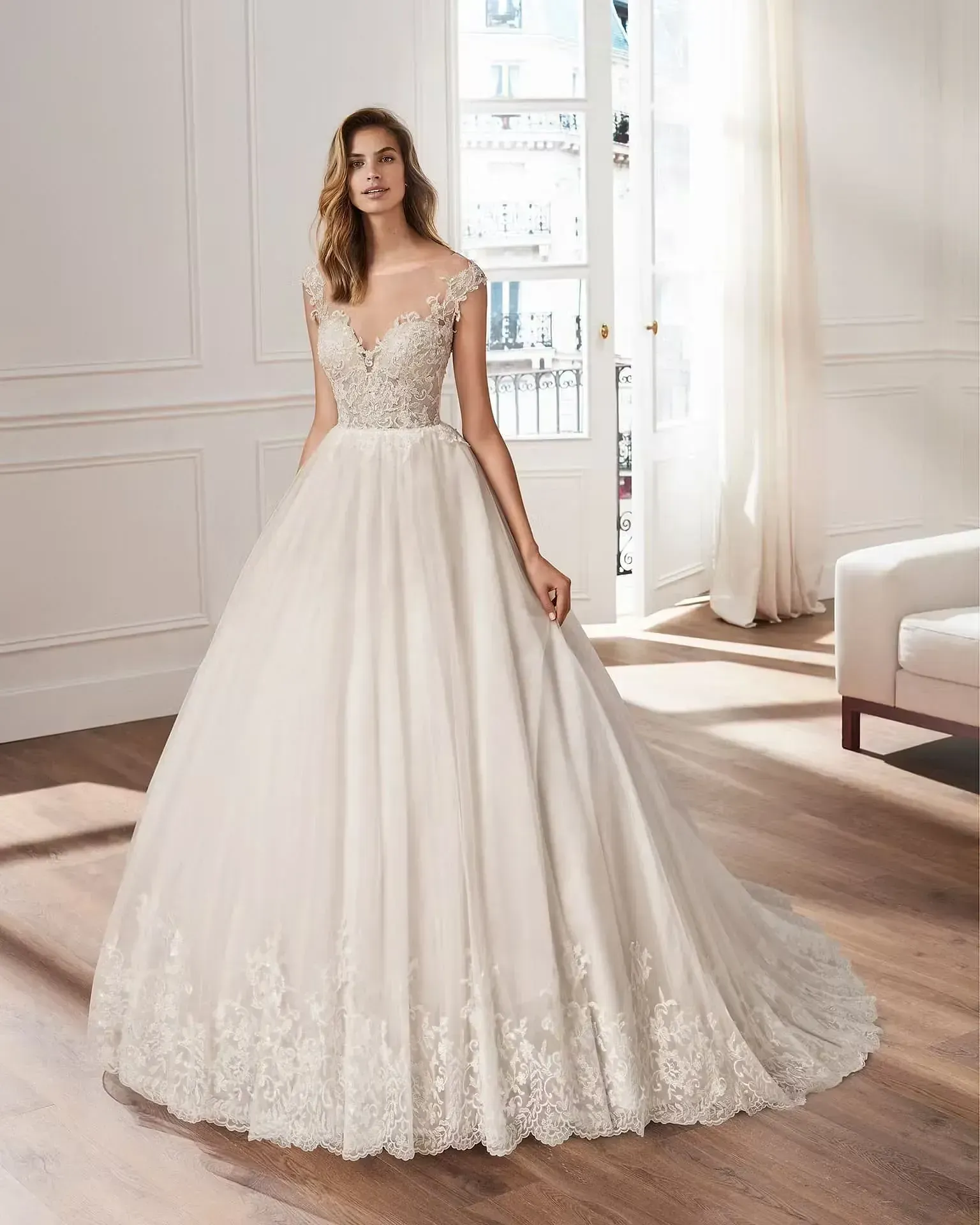 Una mujer lleva un vestido de novia blanco en una sala de estar.