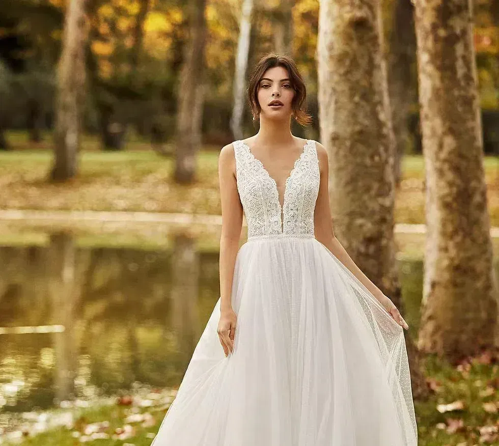 Una mujer con un vestido de novia blanco está parada frente a un lago.