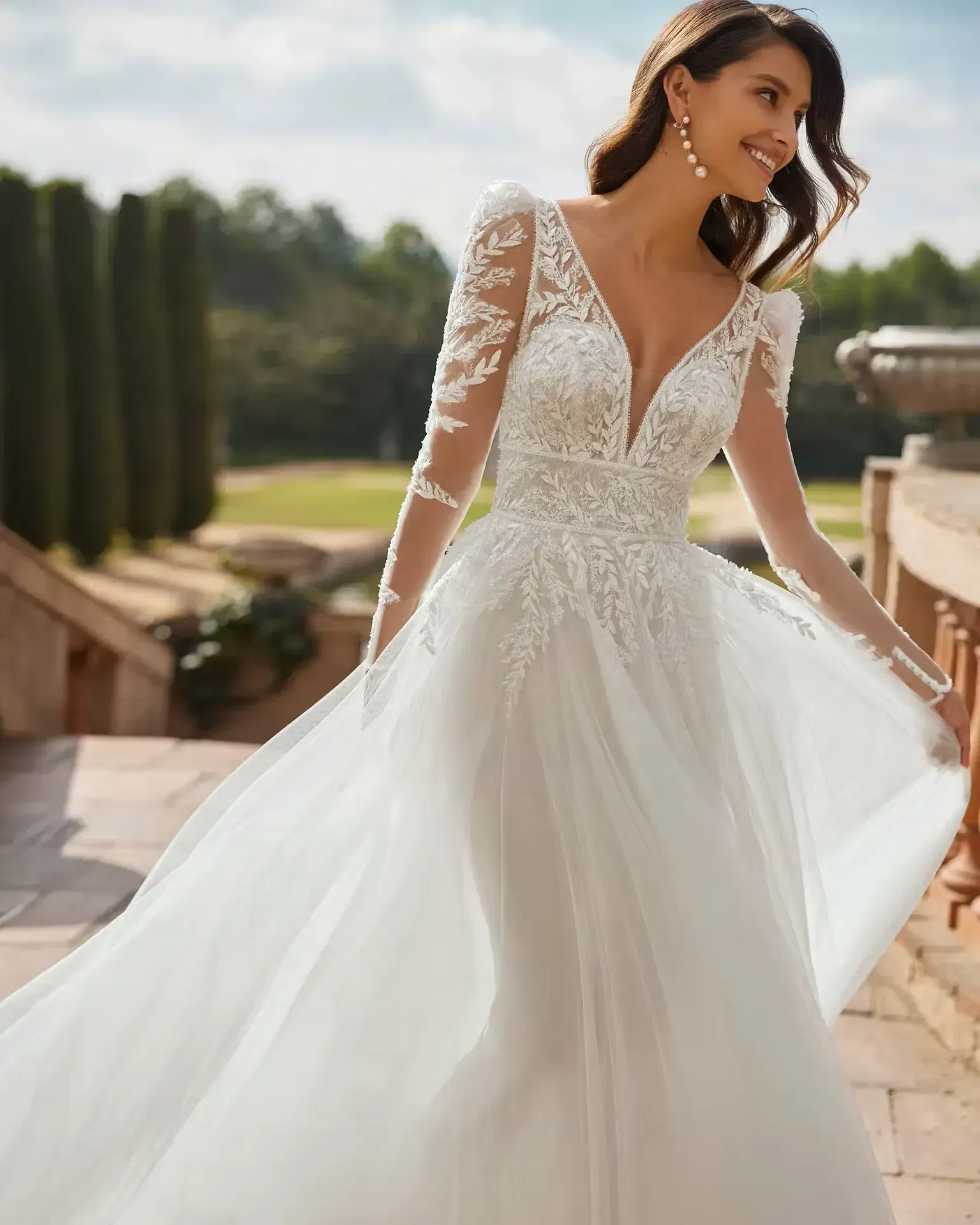 Una mujer lleva un vestido de novia blanco con mangas largas.