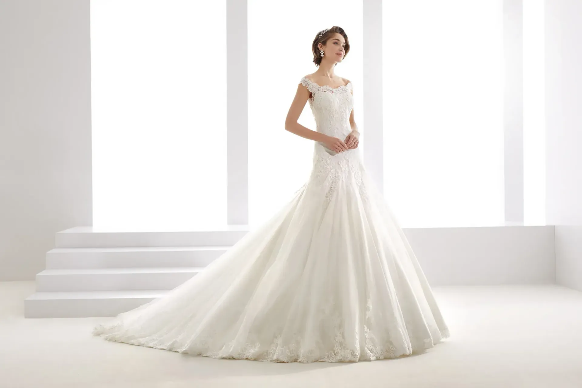 Una mujer con un vestido de novia blanco está parada frente a una ventana.
