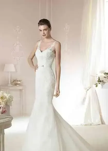 Una mujer con un vestido de novia blanco está de pie en una habitación.
