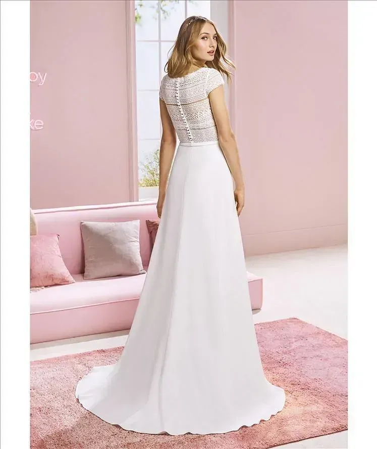 Una mujer con un vestido de novia blanco está parada frente a un sofá rosa.