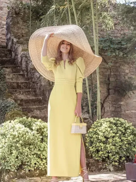 La mujer lleva un vestido amarillo y un sombrero grande.