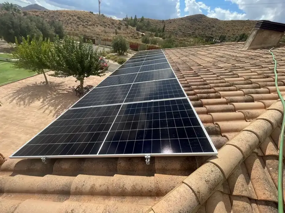 Paneles solares sobre un tejado de tejas de terracota, al aire libre en un día soleado.