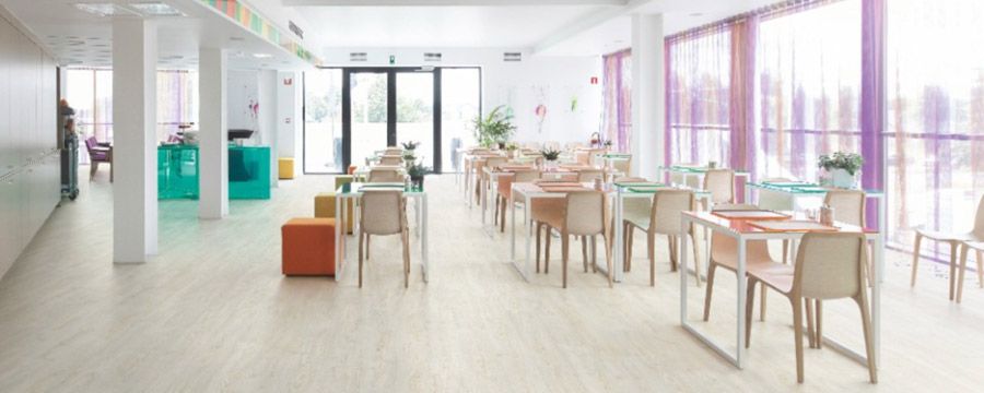 Un comedor luminoso y moderno con muebles coloridos y cortinas translúcidas.