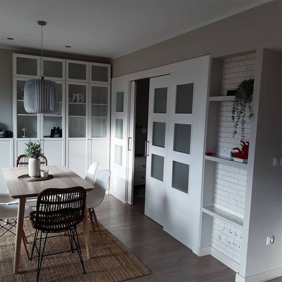 Comedor con mesa, sillas, muebles de almacenaje y puertas corredizas abiertas.