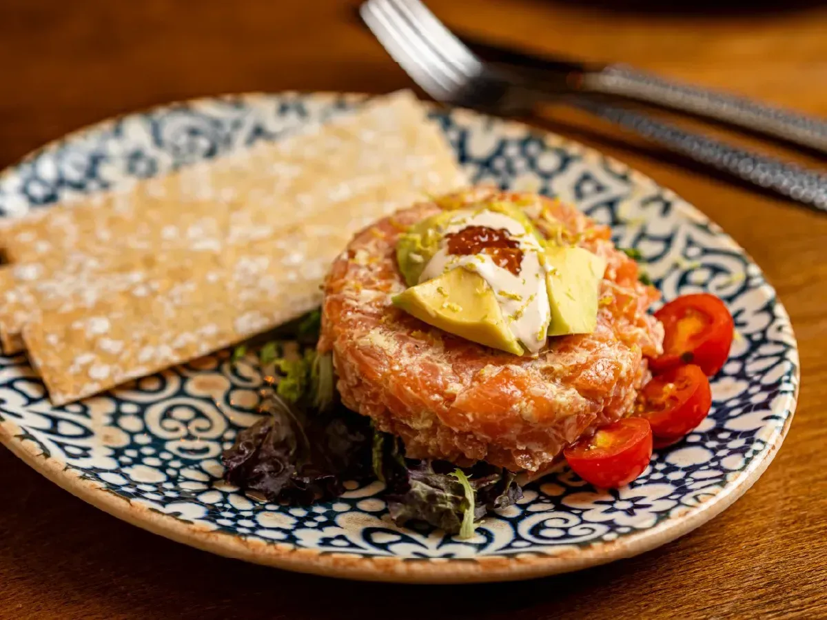 Un plato de comida con aguacate, tomates y galletas en una mesa.