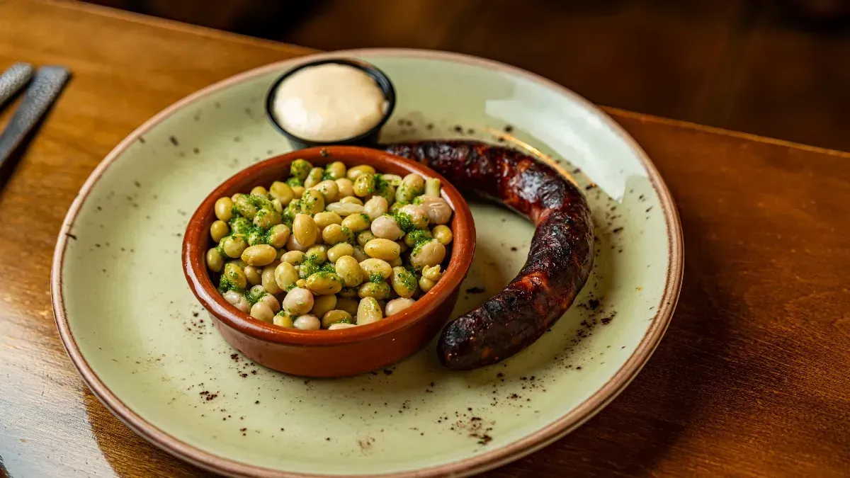 Un plato de comida con una salchicha y frijoles en una mesa.