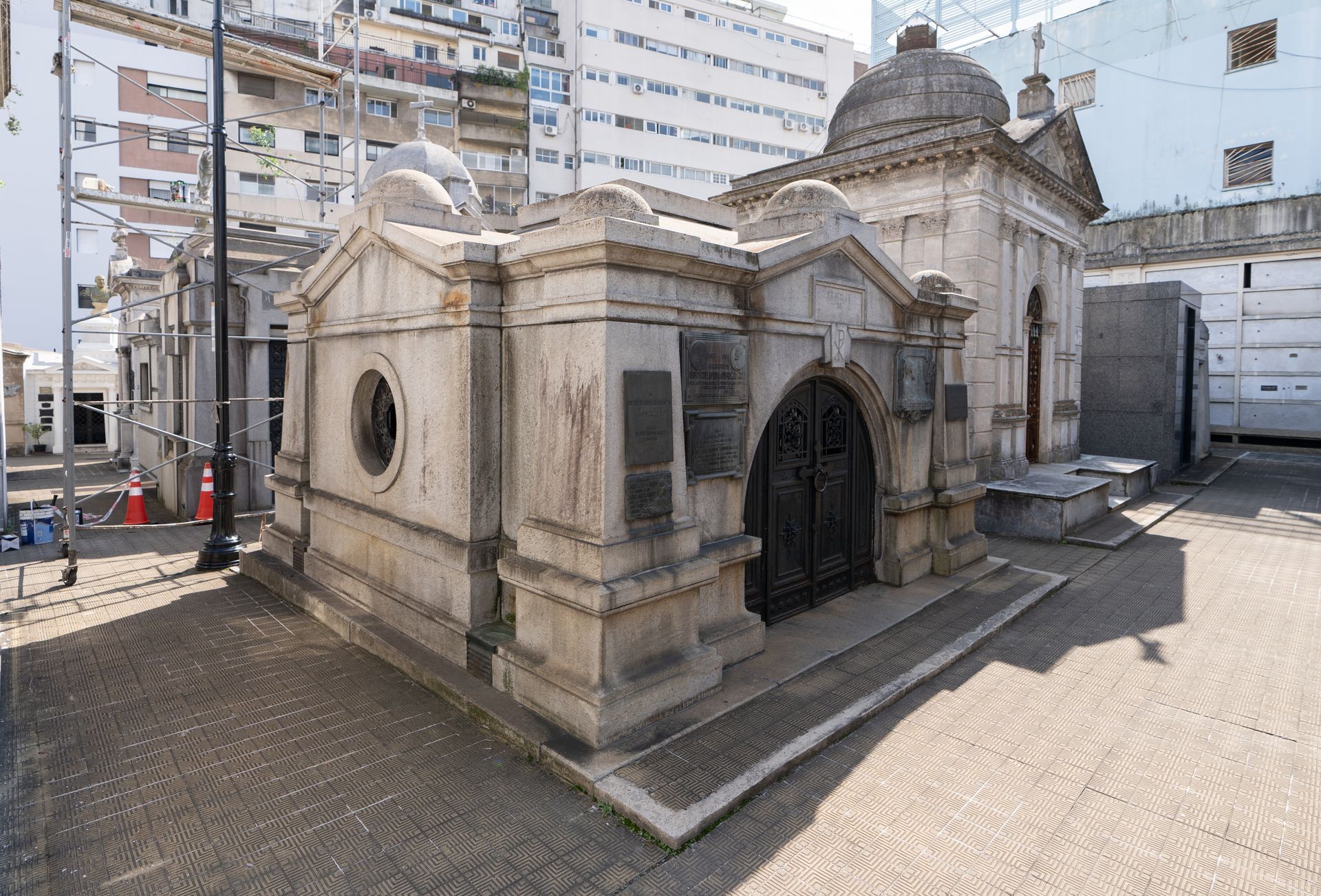 Mausolée en pierre avec entrée voûtée et dôme, situé dans un cimetière municipal.