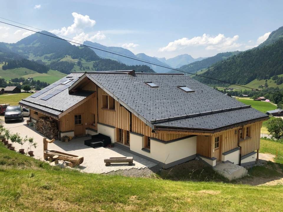 Chalet de montagne avec toit gris, bardage en bois et terrasse en béton.